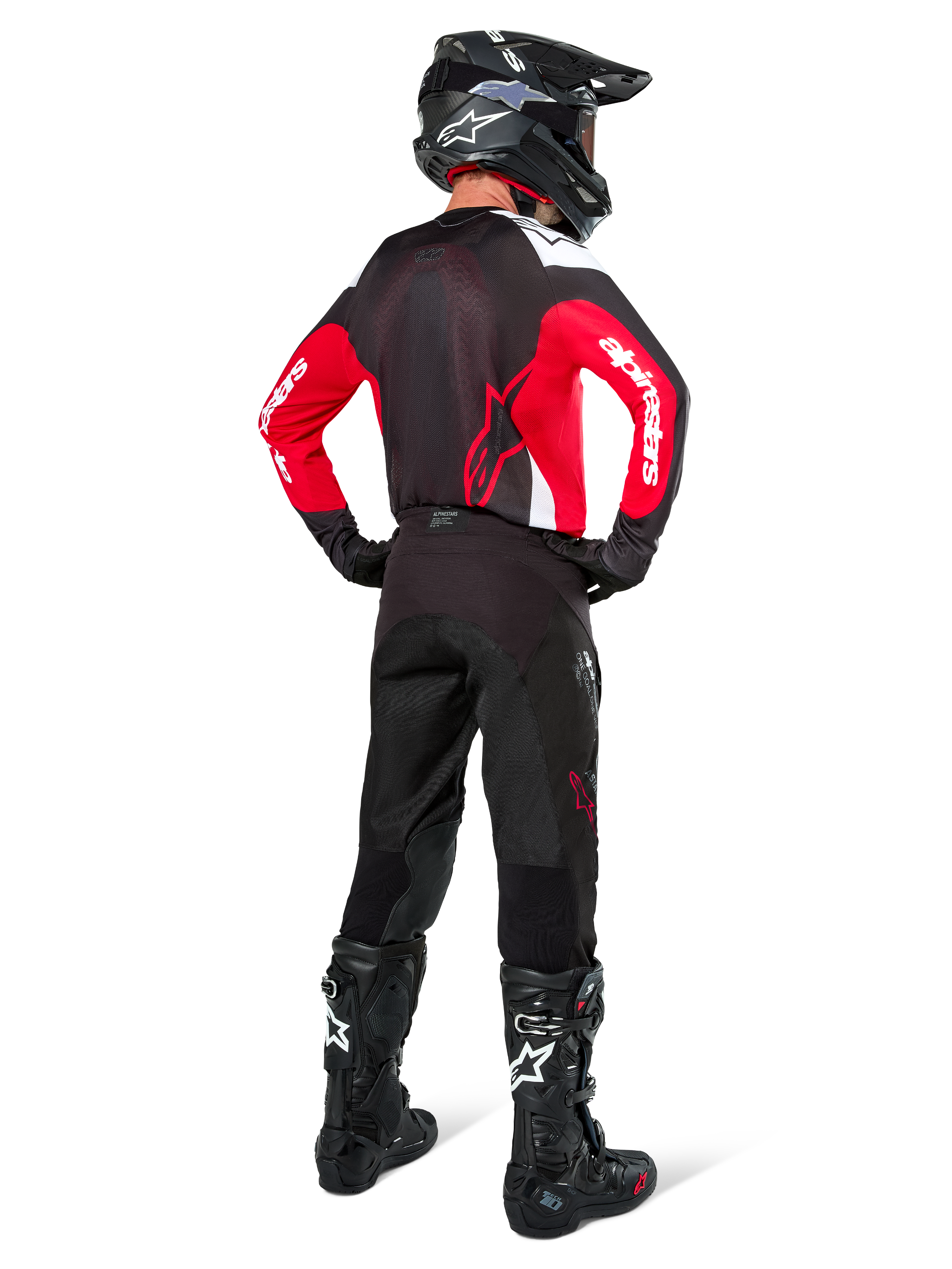 Motocross-Fahrer von hinten in Alpinestars Pro-Dura Hose in Black Magnet White, kombiniert mit einem rot-schwarzen Trikot und schwarzen Stiefeln, abgestimmtes Offroad-Ausrüstungsset für Enduro-Fahrten