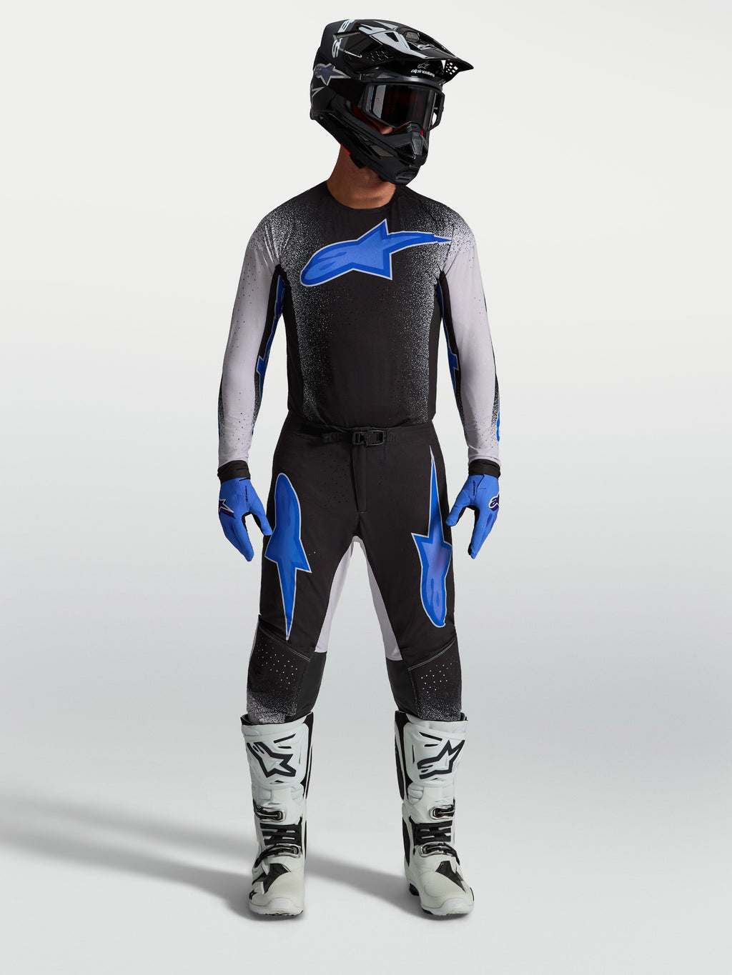 Alpinestars Supertech Hiten AFD broek, zwarte en blauwe motocrossbroek op model met bijpassende jersey en witte motorlaarzen.