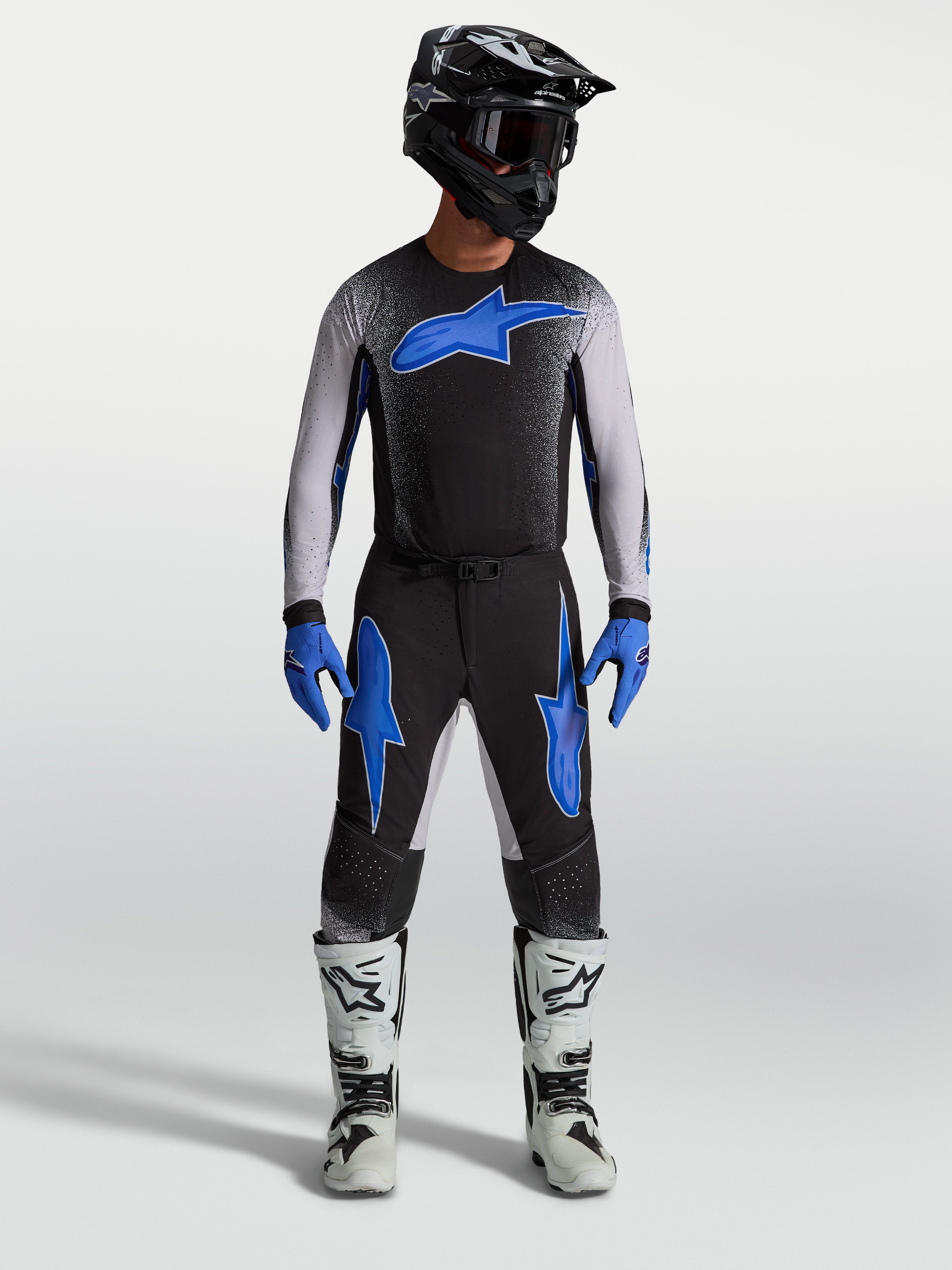 Alpinestars Supertech Hiten AFD broek, zwarte en blauwe motocrossbroek op model met bijpassende jersey en witte motorlaarzen.