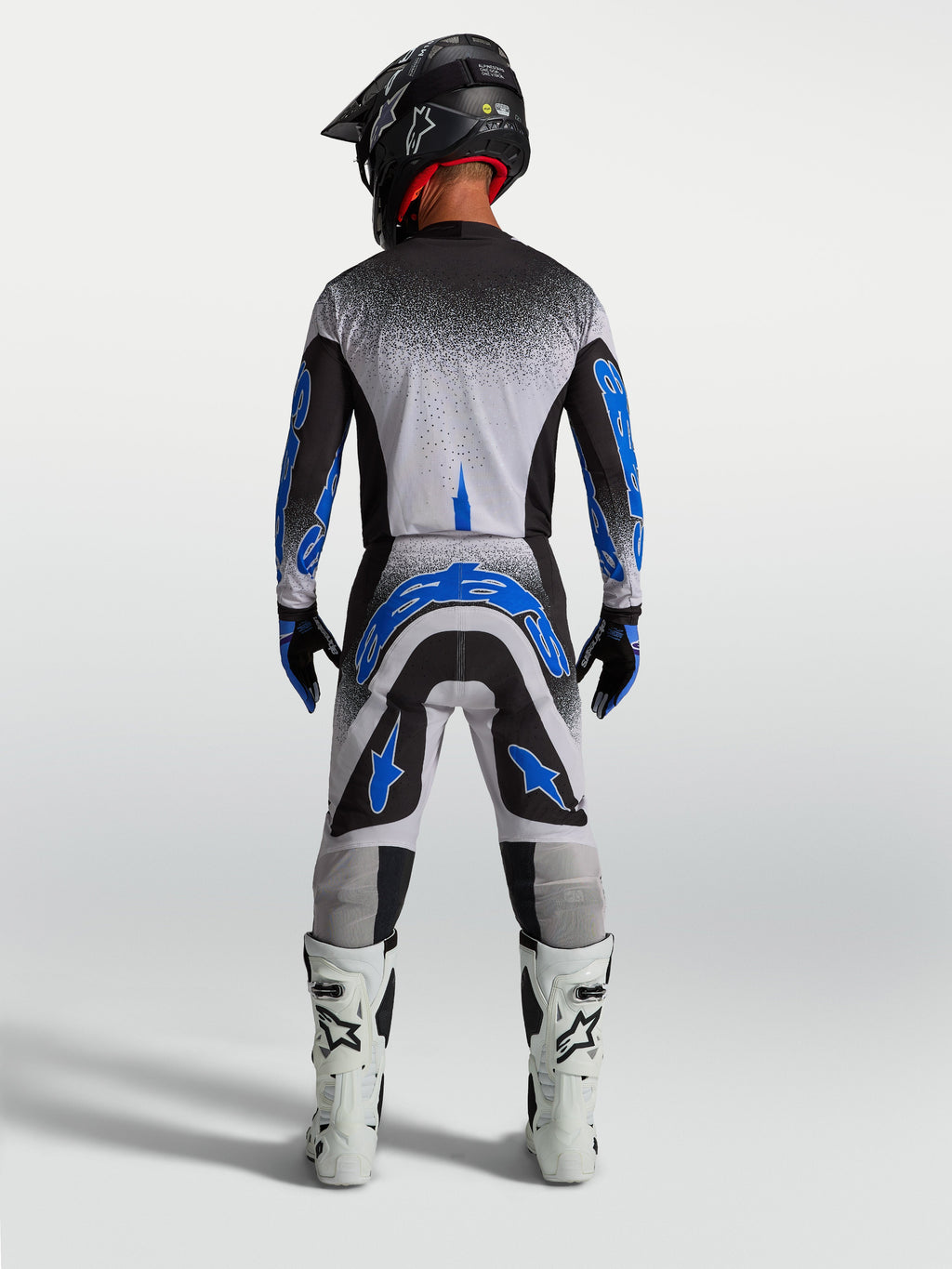 Alpinestars Supertech Hiten AFD broek, heren motocrossbroek in blauw en wit, atletisch achteraanzicht in race-outfit.