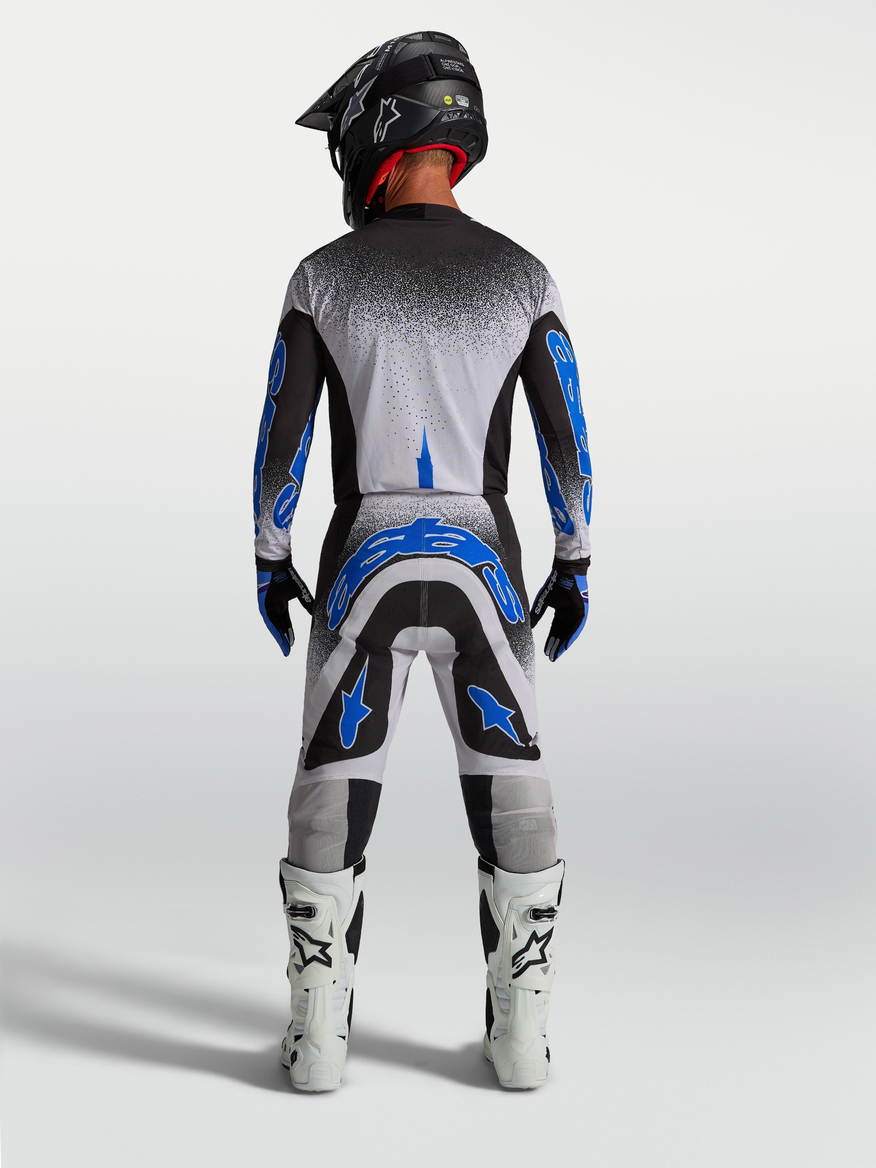 Alpinestars Supertech Hiten AFD broek, heren motocrossbroek in blauw en wit, atletisch achteraanzicht in race-outfit.
