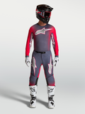 Alpinestars Supertech Hiten AFD Gear Set et Pantalon, tenue de motocross pour homme, gris et rouge fluo, avec bottes blanches.