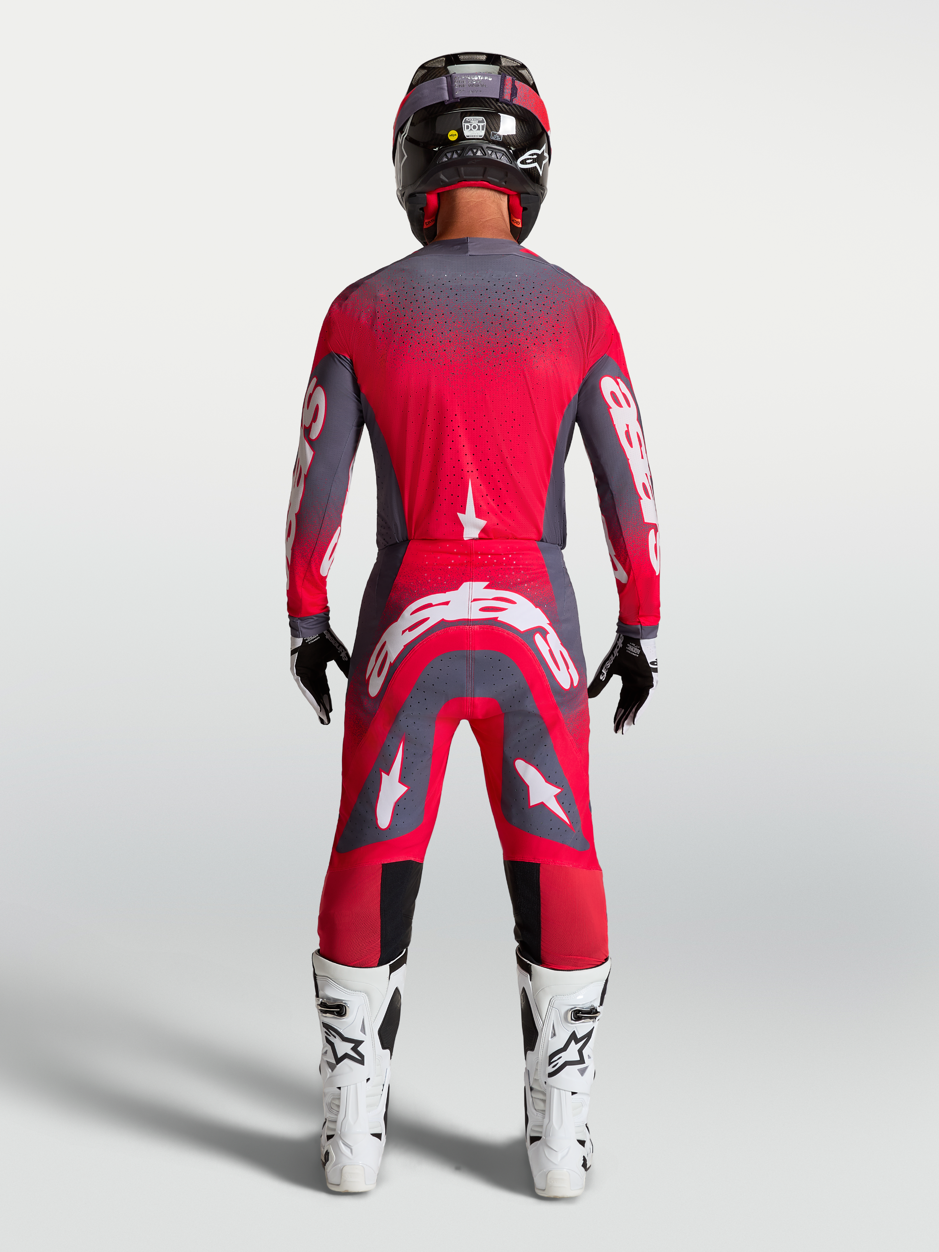 Alpinestars Supertech Hiten AFD gearset en broek, motocross racinguitrusting in neonrood en grijs, achteraanzicht op model.