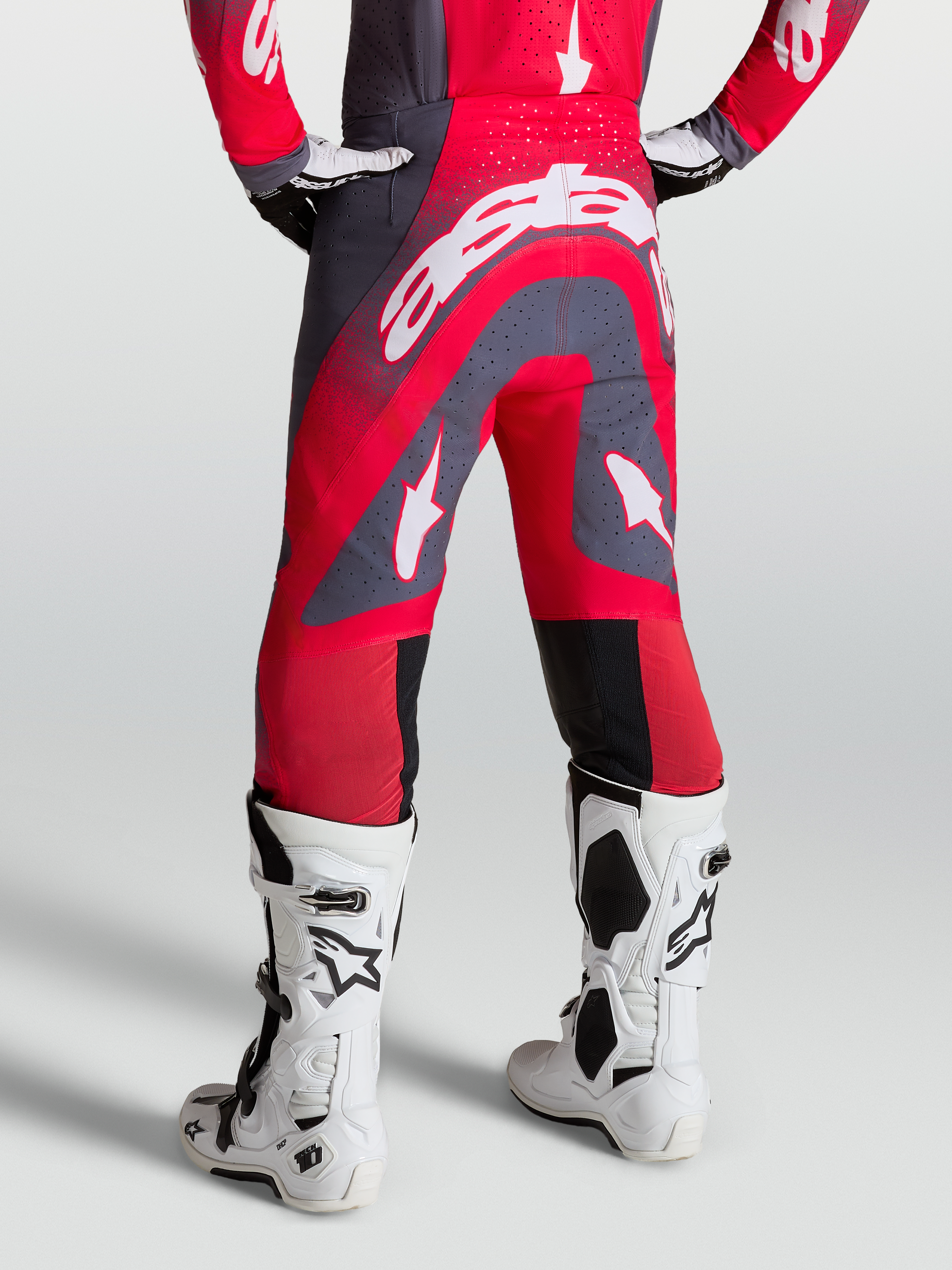Alpinestars Supertech Hiten AFD broek, rood en grijs, motocross-racebroek op model, zijaanzicht met witte race-laarzen.