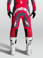 Alpinestars Supertech Hiten AFD Broek, professionele motocrossbroek, rood en grijs met witte logo's, gedragen met witte laarzen.