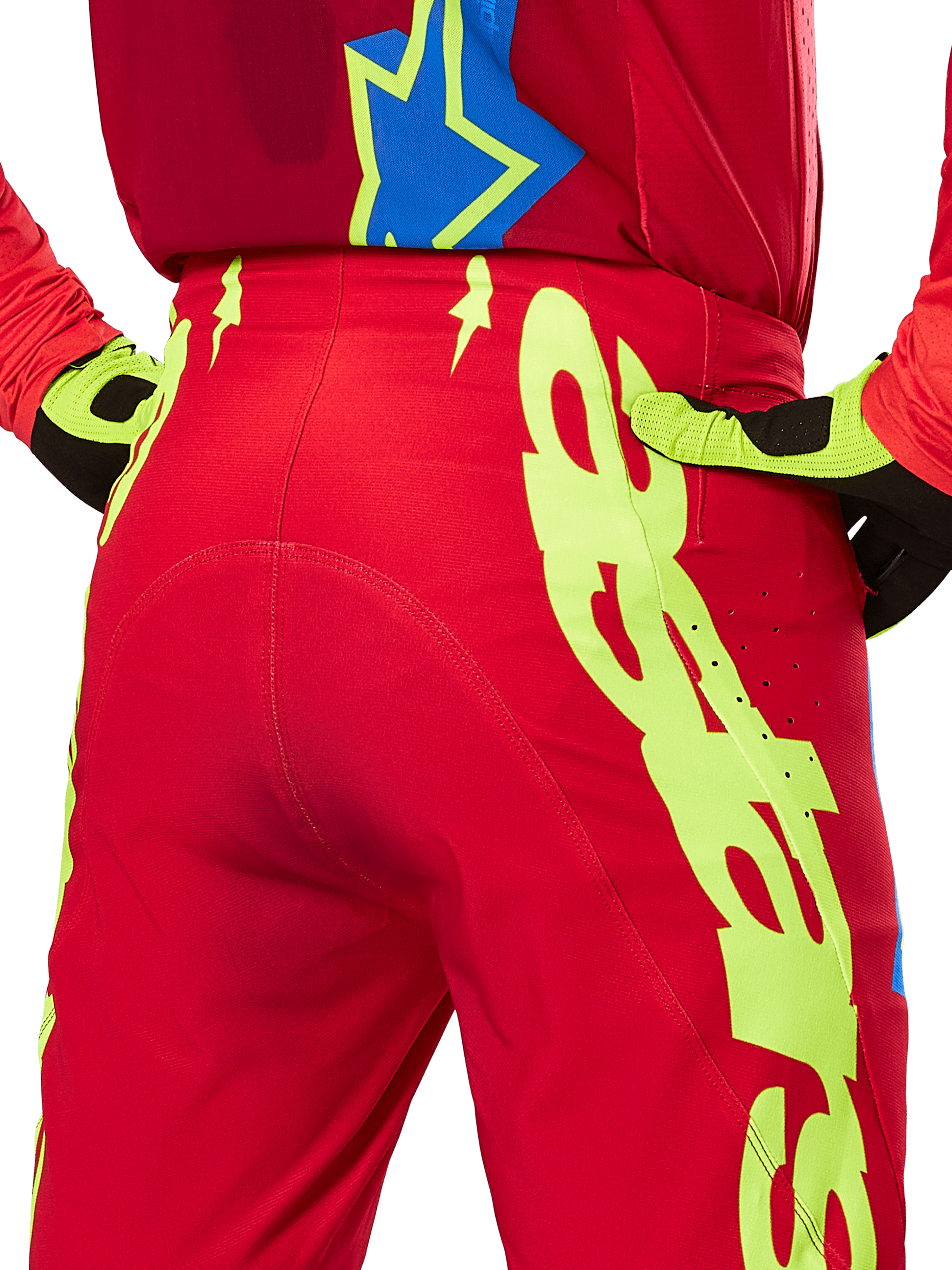 Alpinestars 2025 Supertech Maker Hose, Motocross-Hose, Hellrot und Gelb Fluo, rückseitige Nahaufnahme mit markanten neongelben Grafiken, getragen mit passendem rotem Trikot und gelb-schwarzen Handschuhen