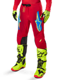 Alpinestars 2025 Supertech Maker Hose, Motocross-Hose, leuchtendes Rot mit blauen und gelben Stern-Logos, schwarze Knieeinsätze, perforierte Belüftung, kombiniert mit neongelben Stiefeln und Handschuhen