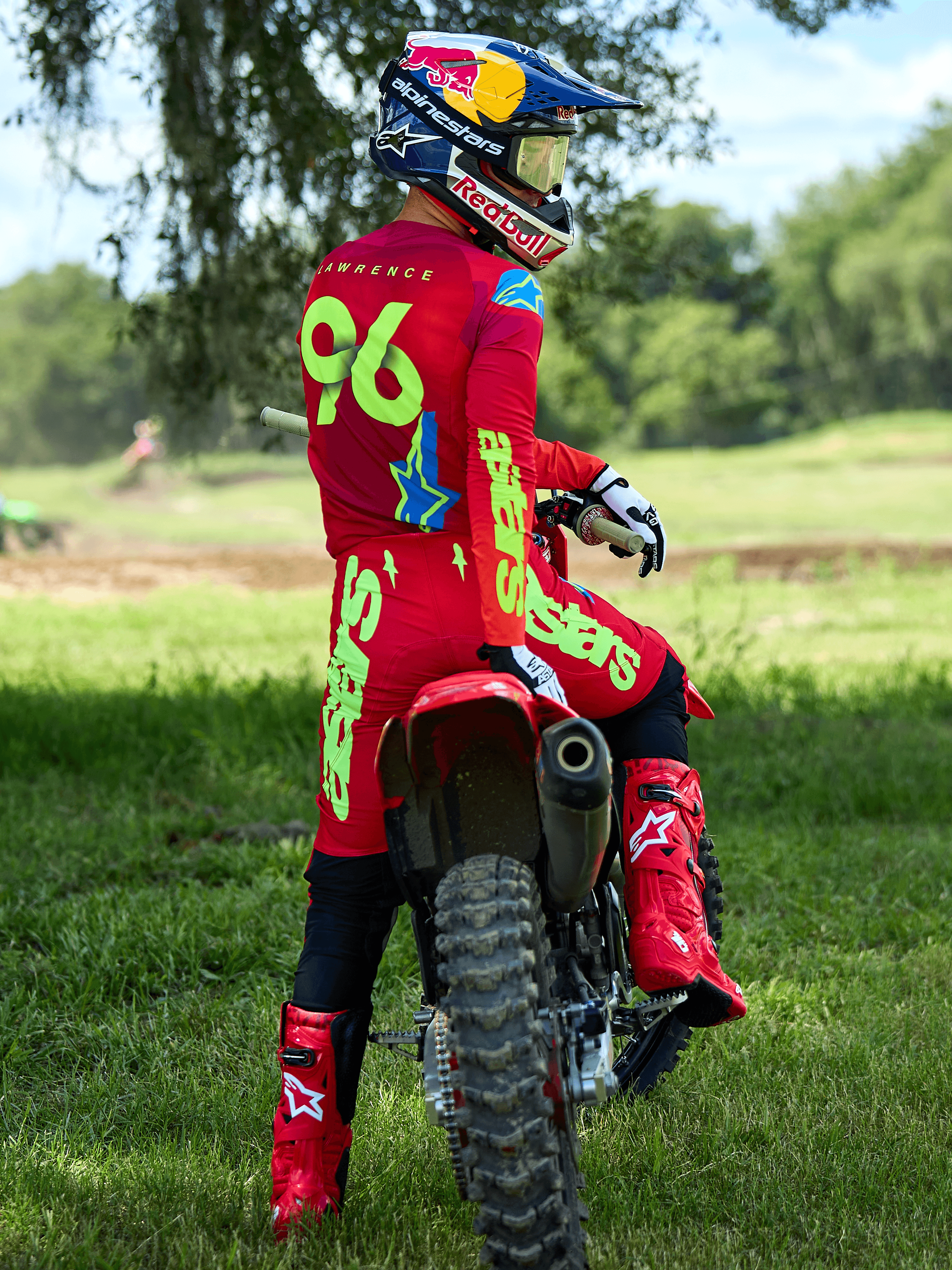 Motocross-Fahrer im Alpinestars 2025 Supertech Maker Ausrüstungsset in Hellrot und Gelb Fluo, sitzend auf einem roten Dirtbike, mit der Trikotnummer 96, passenden roten Stiefeln und Helm, professionelle Rennausrüstung für Offroad-Performance