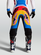 Pantalons Supertech Dyna Alpinestars, pantalons de motocross bleus et jaunes, design multicolore porté par un mannequin, matériau rip-stop extensible et léger