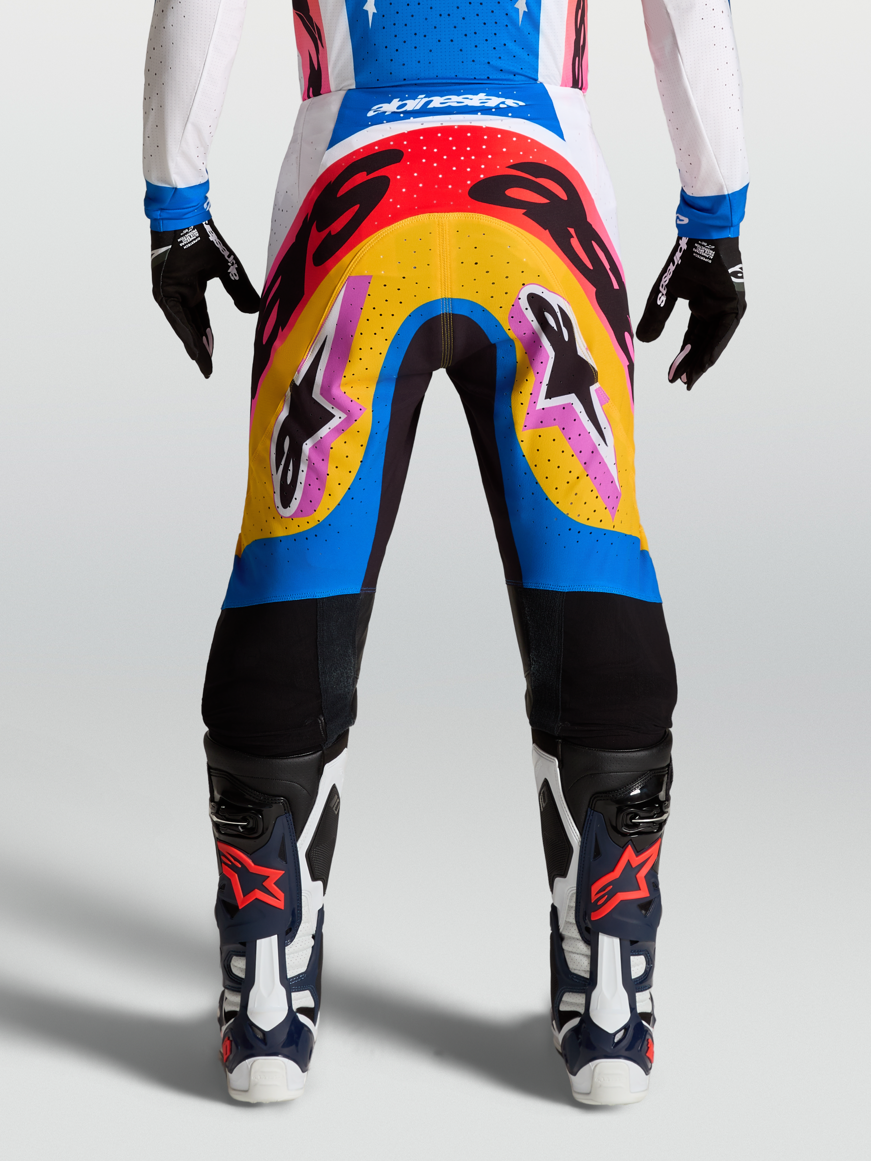Pantalons Supertech Dyna Alpinestars, pantalons de motocross bleus et jaunes, design multicolore porté par un mannequin, matériau rip-stop extensible et léger