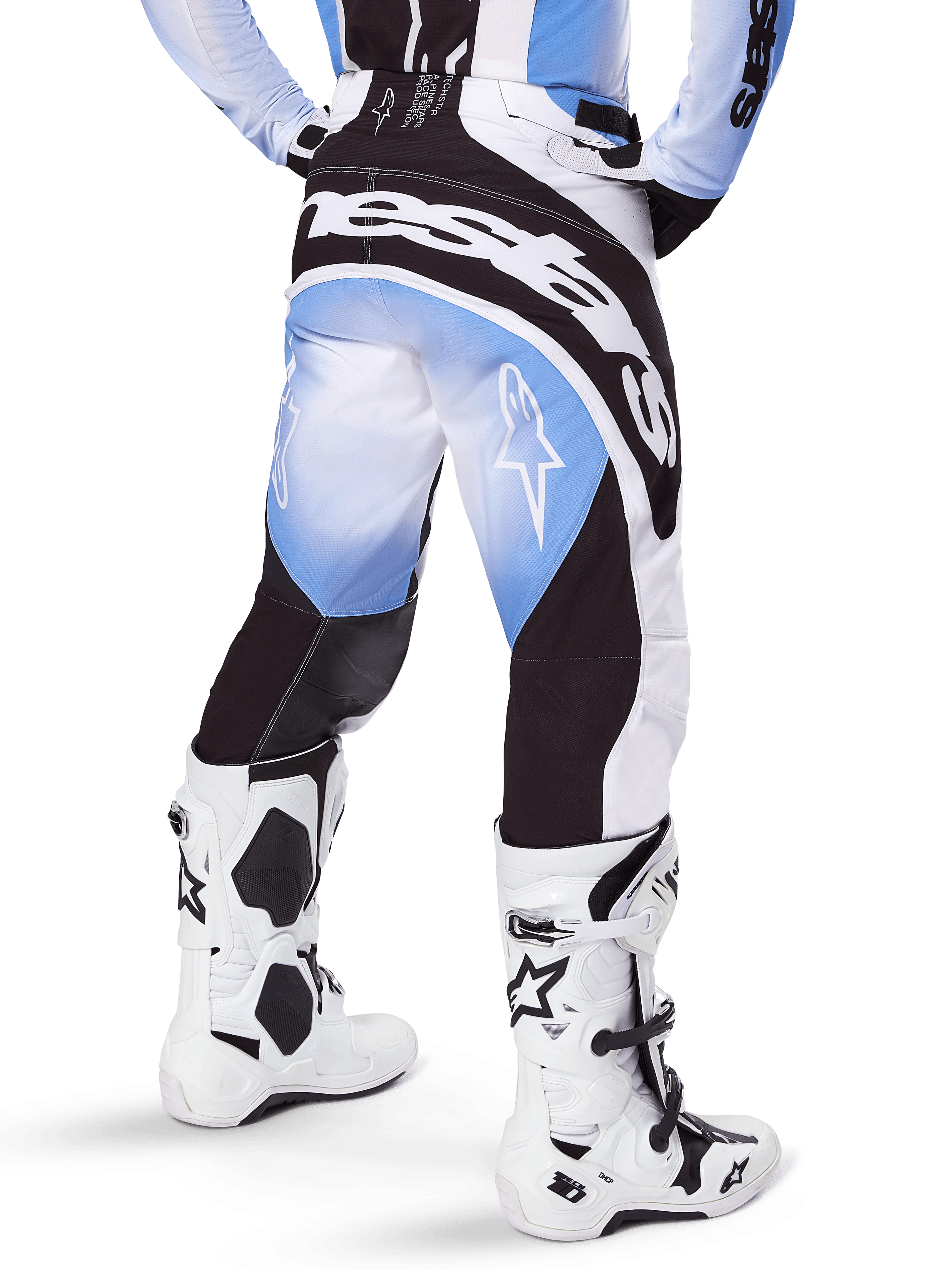 Alpinestars Pantalon Techstar Melt 2025, pantalon de motocross, noir, bleu et blanc, vue arrière avec logo Alpinestars imposant sur l'assise et logos étoiles sur les jambes, porté avec des bottes Tech 10 blanches et noires, équipement de course tout-terrain professionnel