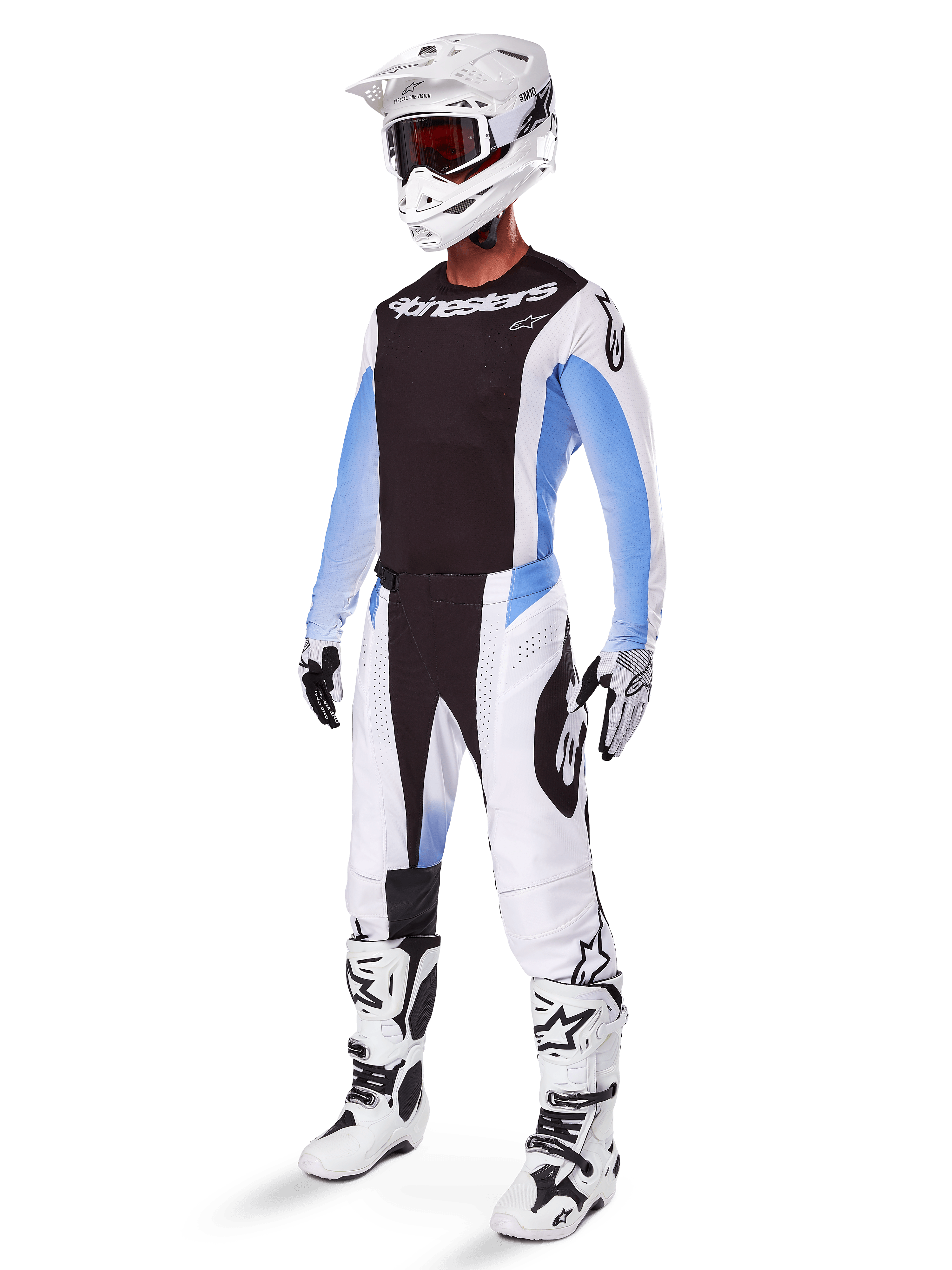 Pilote de motocross portant le pantalon Alpinestars Techstar Melt 2025, tenue de motocross blanche et noire avec des accents bleu clair, maillot et gants coordonnés, casque et lunettes blancs, bottes de course blanches et noires, équipement tout-terrain professionnel.