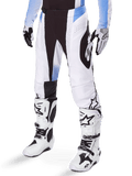 Alpinestars 2025 Techstar Melt Pants, pantalon de motocross, blanc et noir avec des accents bleus, avec perforations laser pour la ventilation et construction de genou Babel, porté avec des bottes et des gants de motocross blancs assortis, design de course tout-terrain athlétique