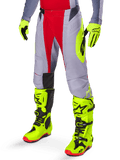 Pantalon Alpinestars Techstar Melt 2025, pantalon de motocross, rouge vif et gris, avec graphismes latéraux jaune fluo et empiècements noirs aux genoux, associé à des bottes et des gants jaune fluo assortis, conçu pour la performance en compétition tout-terrain