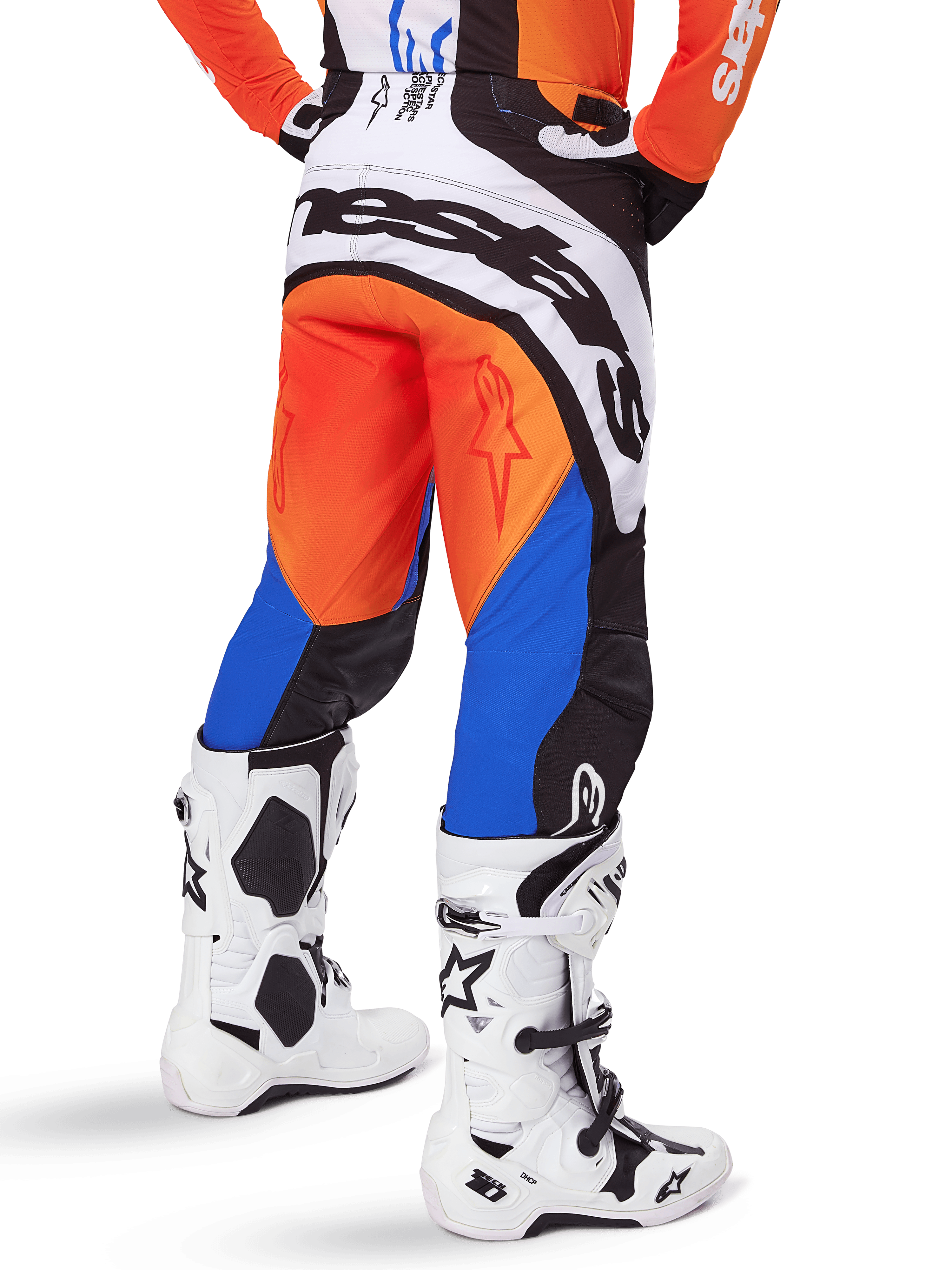 Alpinestars 2025 Techstar Melt broek, motorcross broek, oranje en blauw, van achteren gezien, met groot wit logo op het zitvlak, gedragen met bijpassend oranje shirt en witte Tech 10 laarzen, duurzame off-road race-uitrusting