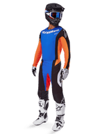 Alpinestars 2025 Techstar Melt Gear Set, motorcrosser met blauwe jersey en oranje mouwen, zwarte broek met blauwe en oranje accenten, bijpassende zwarte helm met blauwe bril, en wit-zwarte racelaarzen