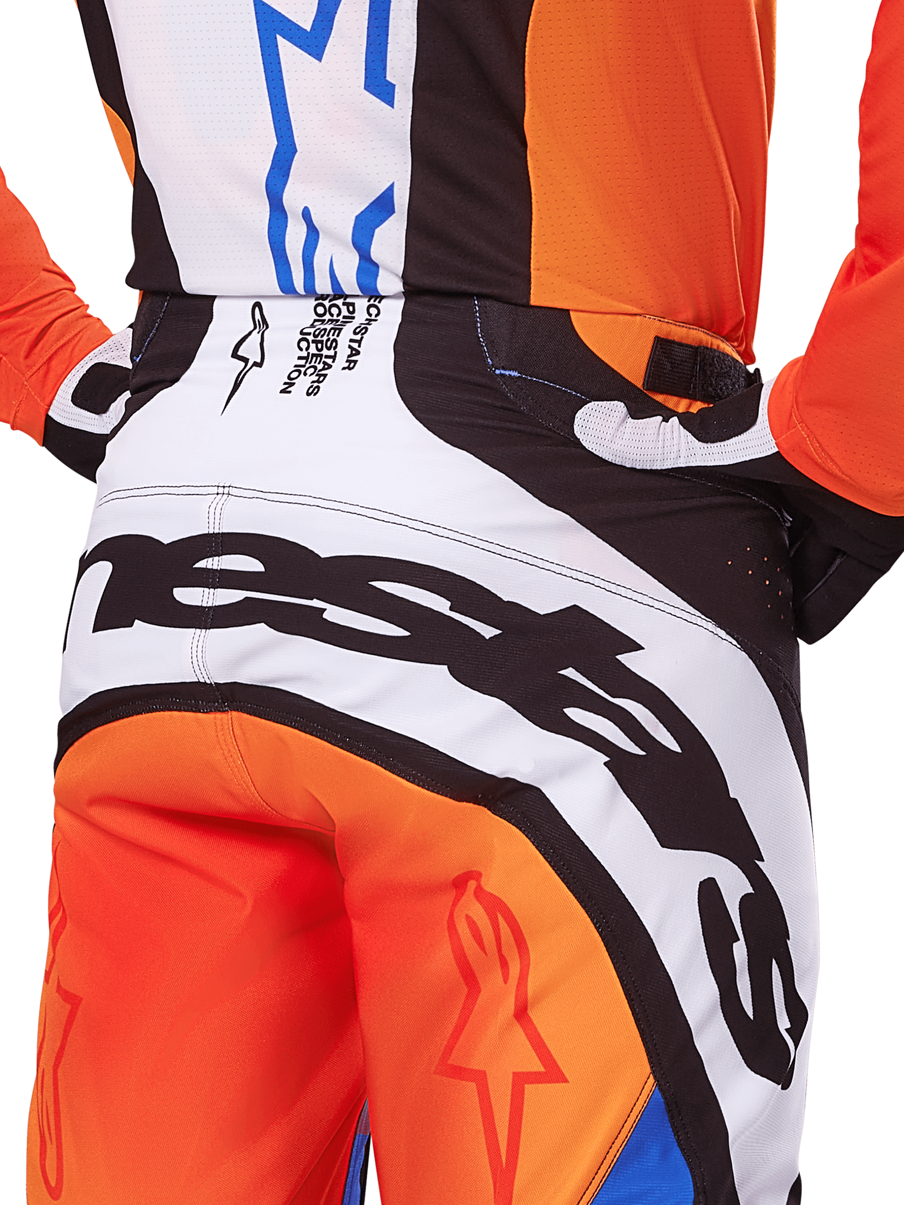 Alpinestars 2025 Techstar Melt crossbroek, motorcross broek, oranje en blauw, close-up achteraanzicht van het zitvlak en de tailleband, opvallende zwarte branding op witte achtergrond, oranje panelen met rode sterlogo's, atletische performance-uitrusting voor off-road racen