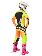 Alpinestars 2025 Techstar Melt Gear Set, motorcrosser van achteren gezien, geel en oranje gradiënt jersey en broek met zwarte panelen, witte helm met rode crossbril, felroze laarzen, gecoördineerde race-outfit voor off-road prestaties