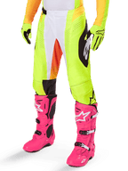 Alpinestars 2025 Techstar Melt crossbroek, motorcross broek, neongeel met witte en oranje accenten, zwarte zijpatronen, gedragen met felroze motorcrosslaarzen en neongele handschoenen, voorzien van geperforeerde ventilatie, duurzame off-road racekleding