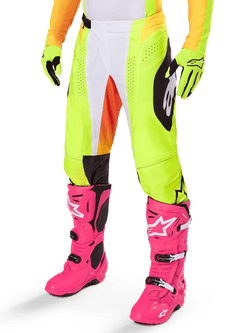Alpinestars 2025 Techstar Melt Pants, Motocross Pants, Neon Yellow with White and Orange Accents, Black Side Patterns, worn with bright pink motocross boots and neon yellow gloves, featuring perforated ventilation, durable off-road racing gear