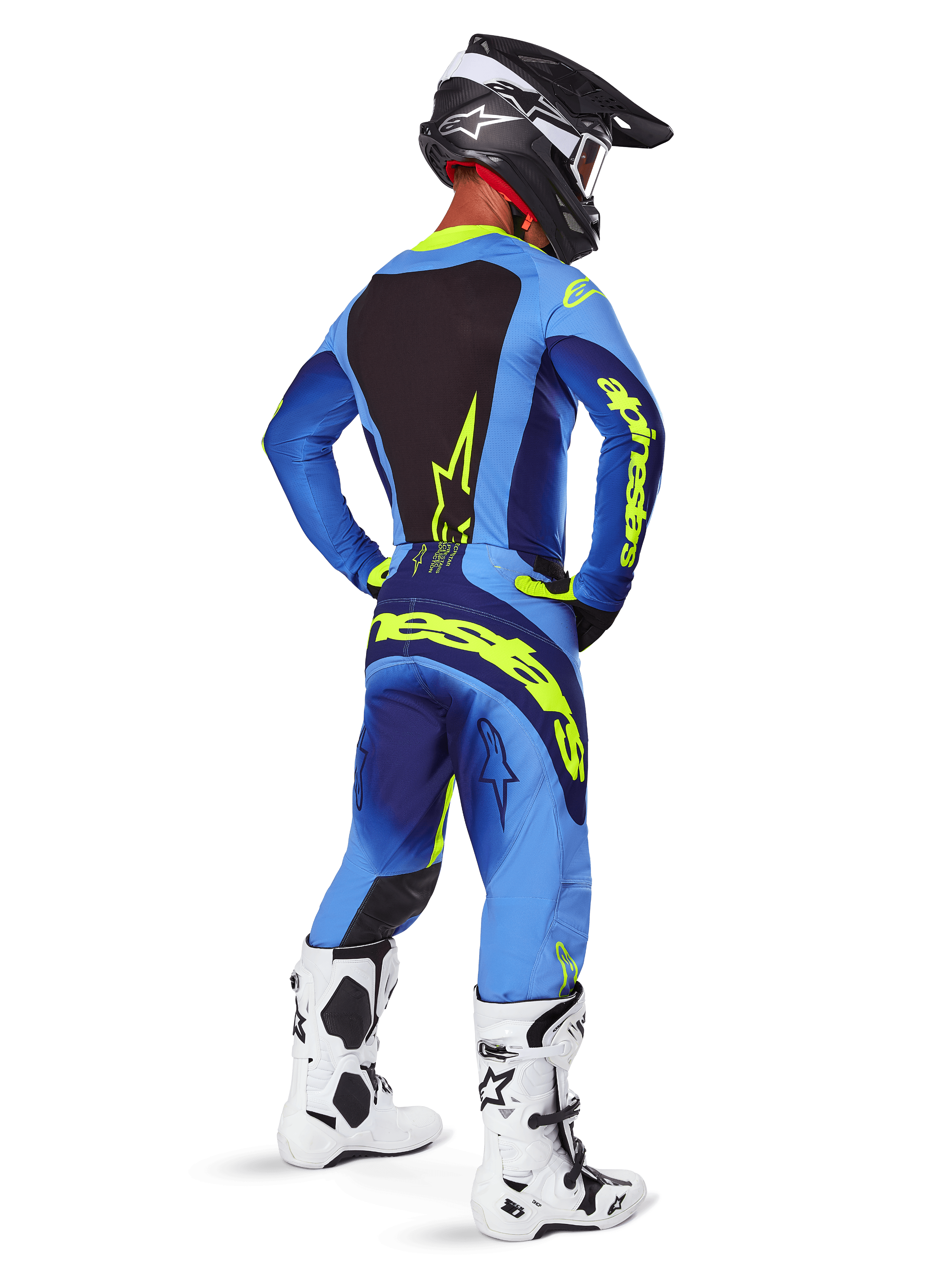Alpinestars 2025 Techstar Melt crossbroek, motorcross kleding, Yellow Fluo Blue, achteraanzicht van een rijder met bijpassende blauwe jersey met opvallende gele branding, witte en zwarte laarzen en zwarte helm, complete race-outfit voor off-road prestaties