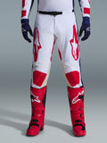Alpinestars 2026 Racer Riway Hose, Motocross-Hose, Wei&szlig;, Blau und Rot, getragen mit roten Stiefeln und dunkelblauen Handschuhen, mit gro&szlig;en roten Logos auf den Oberschenkeln und roten Knieeins&auml;tzen, sportliches, vorgeformtes Design mit verstellbarer Taillenschnalle