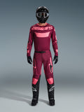 Motocross-Fahrer im Alpinestars 2026 Racer Riway Gear Set, weinrotes Trikot mit pinkem 'astars'-Branding, passende weinrote Hose mit pinken Knie- und Beinakzenten, schwarzer Helm, schwarze Handschuhe und schwarze Stiefel, komplette Performance-Ausrüstung für den Offroad-Rennsport