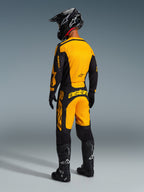 Rear view of a motocross rider wearing the Alpinestars 2026 Racer Riway Pants in Yellow and Black, matching jersey, black helmet, and black boots, coordinated racing gear set for off-road performance