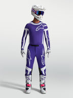 Alpinestars Supertech Vesta Broek, heren-motocrossbroek in donkerblauw en wit, atletische pasvorm en rip-stop stof, gedragen door een model met complete off-road race-uitrusting.