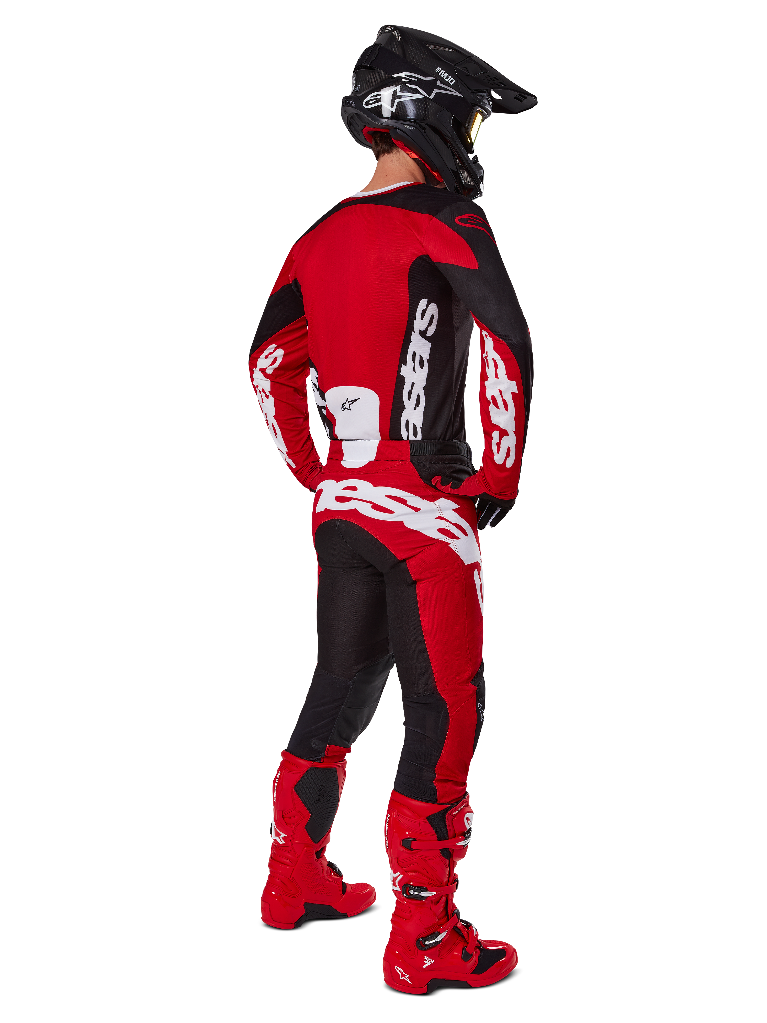 Alpinestars 2025 Racer Veil Gear Set, motocrossrijder van achteren gezien in een rood shirt met zwarte panelen en witte logo's, bijpassende rode en zwarte broek met grote witte merklogo's, rode laarzen en een zwarte helm, complete off-road race-outfit