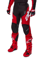 Motorcrosser in Alpinestars 2025 Racer Veil Gear Set, rood en zwart jersey en broek met witte logo's, bijpassende handschoenen en felrode motorcrosslaarzen, gecoördineerde prestatiegerichte uitrusting voor off-road racen