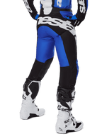 Alpinestars 2025 Racer Veil broek, motorcrossbroek, blauw en zwart, achteraanzicht met grote witte branding op het zitvlak, gedragen met bijpassende jersey en witte laarzen, duurzaam technisch materiaal voor off-road rijden