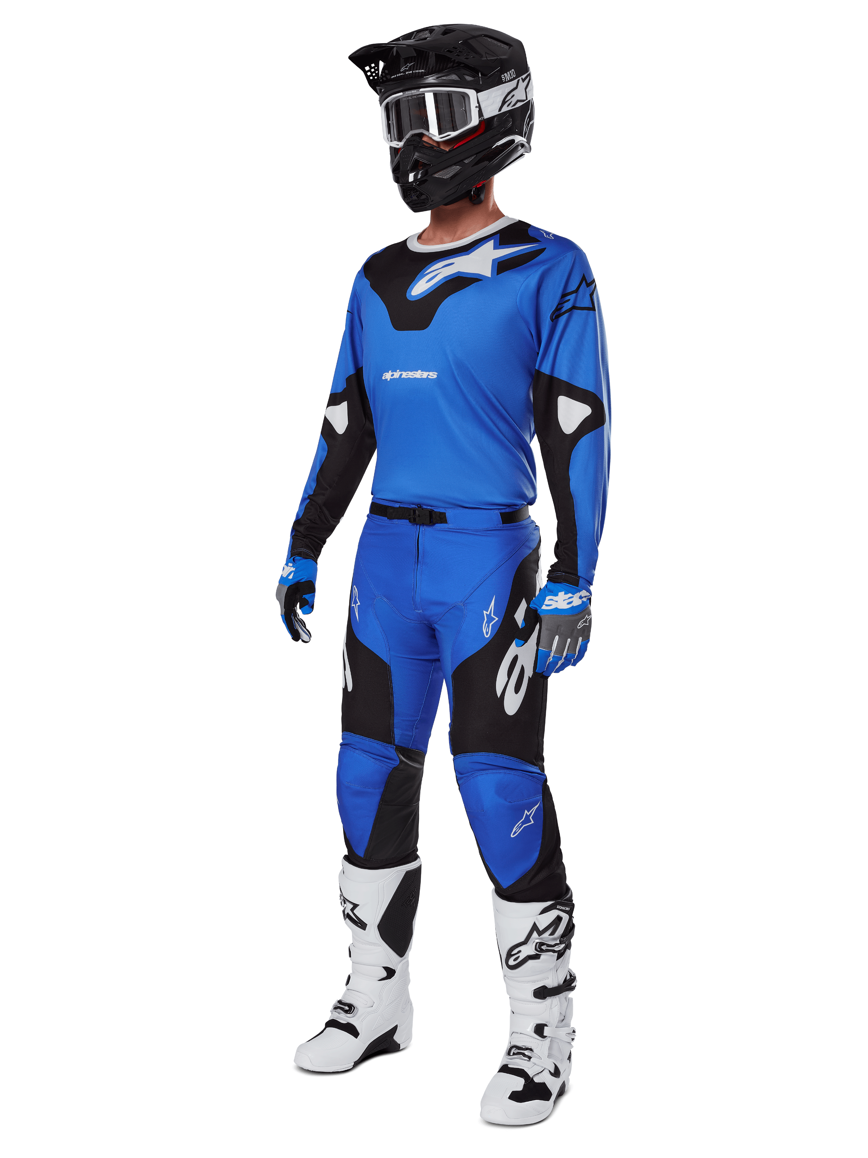 Motocrossrijder in volledige race-uitrusting, met Alpinestars 2025 Racer Veil broek in blauw en zwart, bijpassende blauwe jersey met witte accenten, zwarte helm met witte crossbril, witte en zwarte laarzen en blauwe handschoenen, gecoördineerde outfit voor off-road racing
