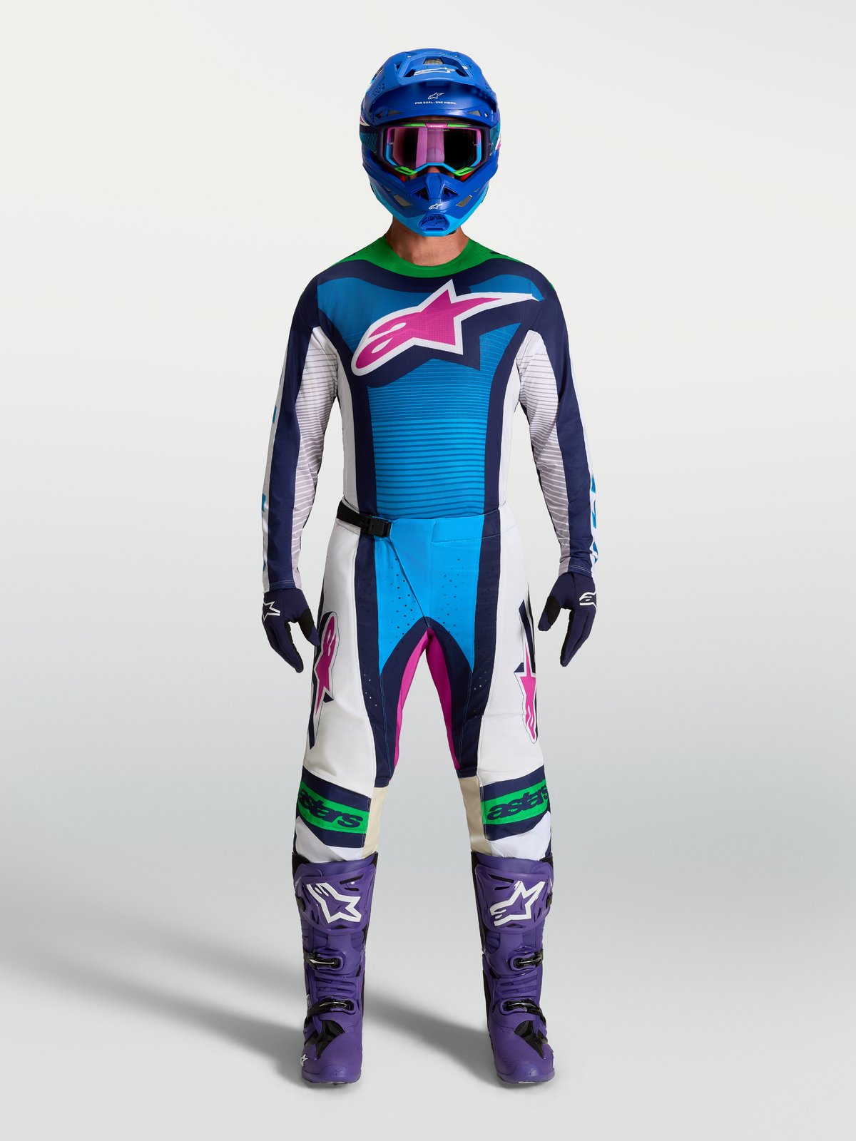 Alpinestars Techstar Maven gear set et pantalon Techstar Maven, tenue de motocross pour homme, bleue et blanche avec accents roses et verts, portée sur mannequin avec casque bleu et bottes violettes