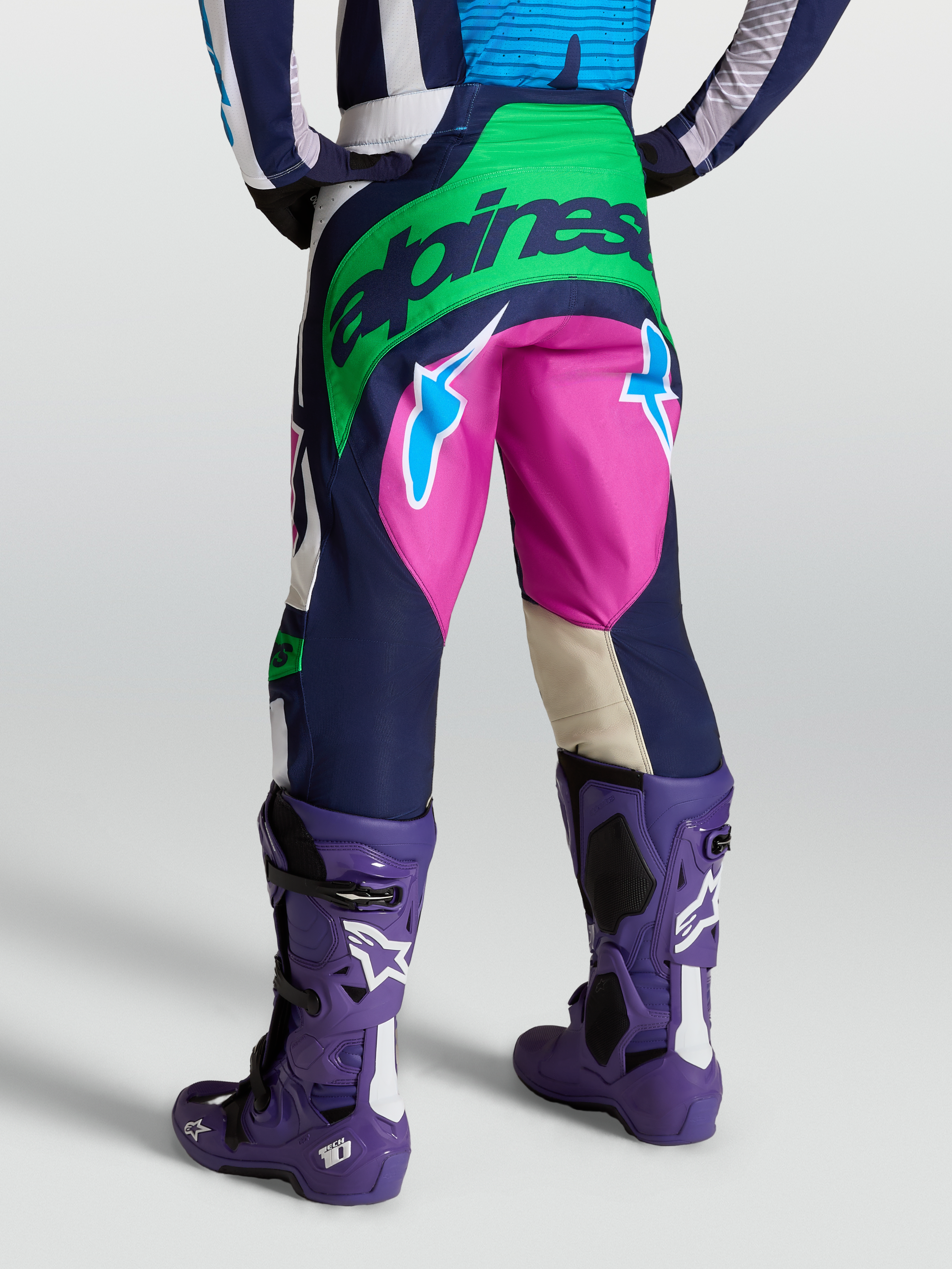 Alpinestars Techstar Maven broek, motorcrossbroek in blauw en groen, achteraanzicht op model met Tech 10 laarzen.