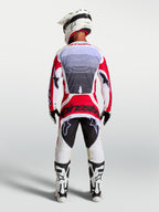 Alpinestars Techstar Maven motocrossbroek, rood en wit, achteraanzicht op een rijder met atletische racepasvorm.