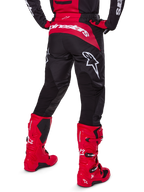 Alpinestars 2025 Fluid Haul Ausrüstungsset, Rückansicht, schwarz-rote Motocross-Hose mit großen weißen Logos, passendes Trikot und leuchtend rote Tech 7 Stiefel, abgestimmtes Offroad-Rennset