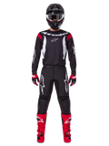 Alpinestars 2025 Fluid Haul Ausrüstungsset, Motocross-Fahrer in kompletter Rennausrüstung, schwarzes Trikot mit roten Schulterakzenten und weißen Logos, schwarze Hose mit weißem Stern-Branding, leuchtend rote Stiefel, rot-schwarze Handschuhe, schwarzer Helm mit weißer Brille, abgestimmter Offroad-Performance-Look