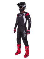 Motocross-Fahrer im kompletten Alpinestars 2025 Fluid Haul Ausrüstungsset, schwarzes Jersey mit roten und weißen Akzenten, schwarze Hose mit weißen Logos, leuchtend rote Stiefel, rote und schwarze Handschuhe, schwarzer Helm mit Brille, abgestimmte Offroad-Performance-Ausrüstung