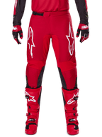 Alpinestars 2025 Fluid Haul Pants, pantalon de motocross, rouge vif et noir, doté de grands logos blancs sur les cuisses et d'empiècements noirs à l'intérieur des jambes, porté avec des bottes et des gants rouges assortis, coupe athlétique pour la performance en motocross