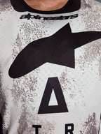 Alpinestars 2026 Racer Lahnd Jersey, motorcross jersey, wit en grijs gespikkeld patroon, close-up van de borst met groot zwart Astars-logo en Alpinestars-branding op de halslijn, prestatiegericht ontwerp voor off-road rijden