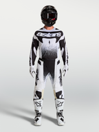 Alpinestars Techstar Swan broek en jersey, wit en zwarte motocross-set gedragen door een model.