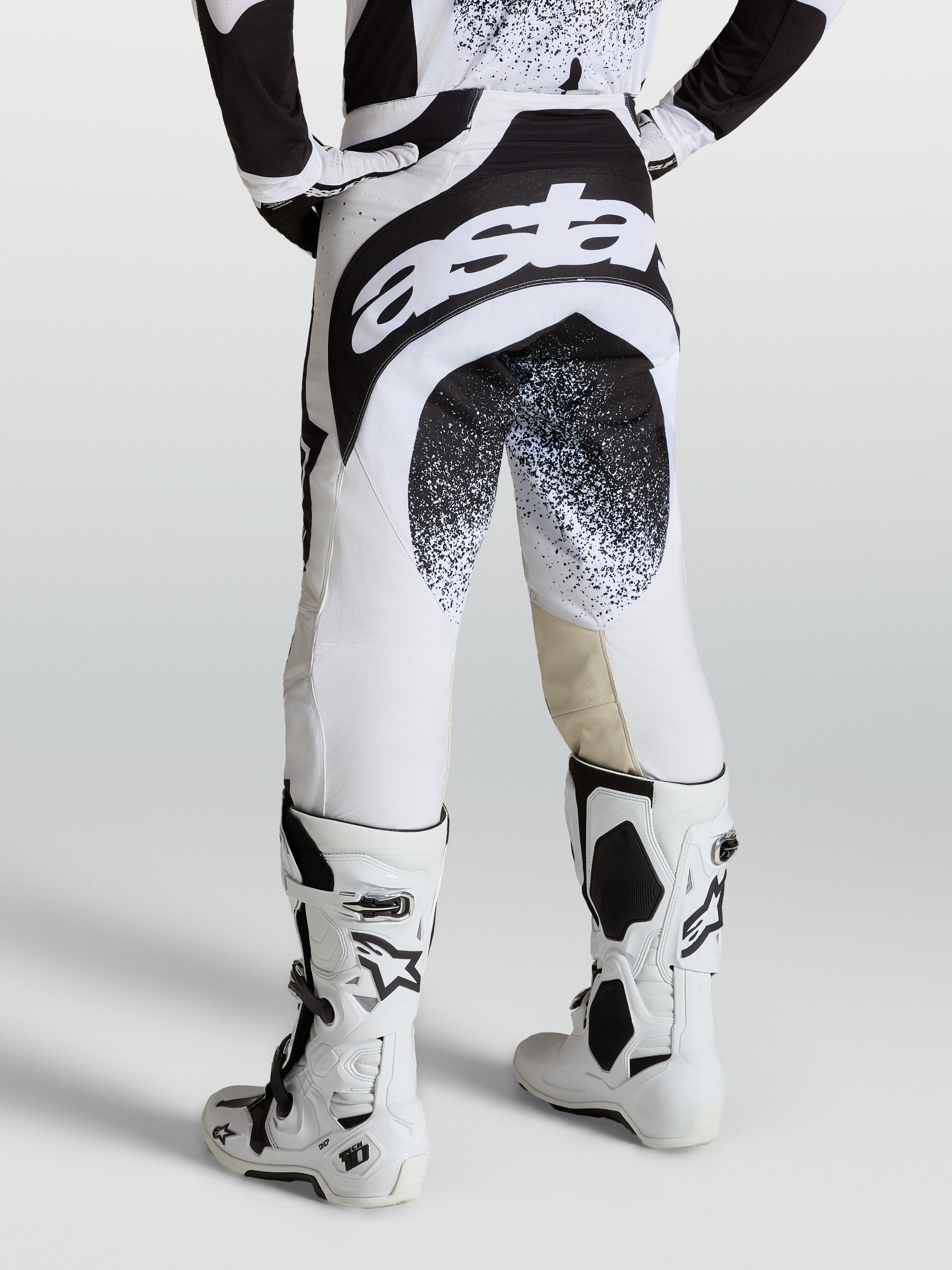 Alpinestars Techstar Swan broek, professionele motorcrossbroek voor heren, zwart en wit, met Astar-branding en versterkt zitvlak, gedragen op model.