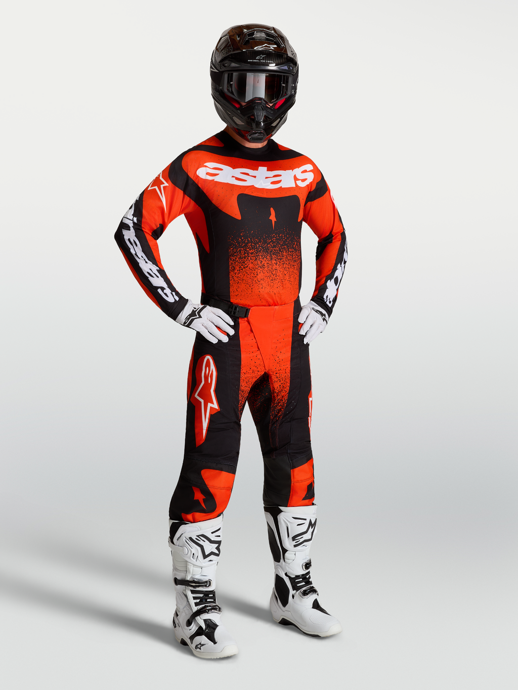 Alpinestars Techstar Swan broek, heren-motorcrossbroek in rood, zwart en wit, gedragen met bijpassende jersey en laarzen.