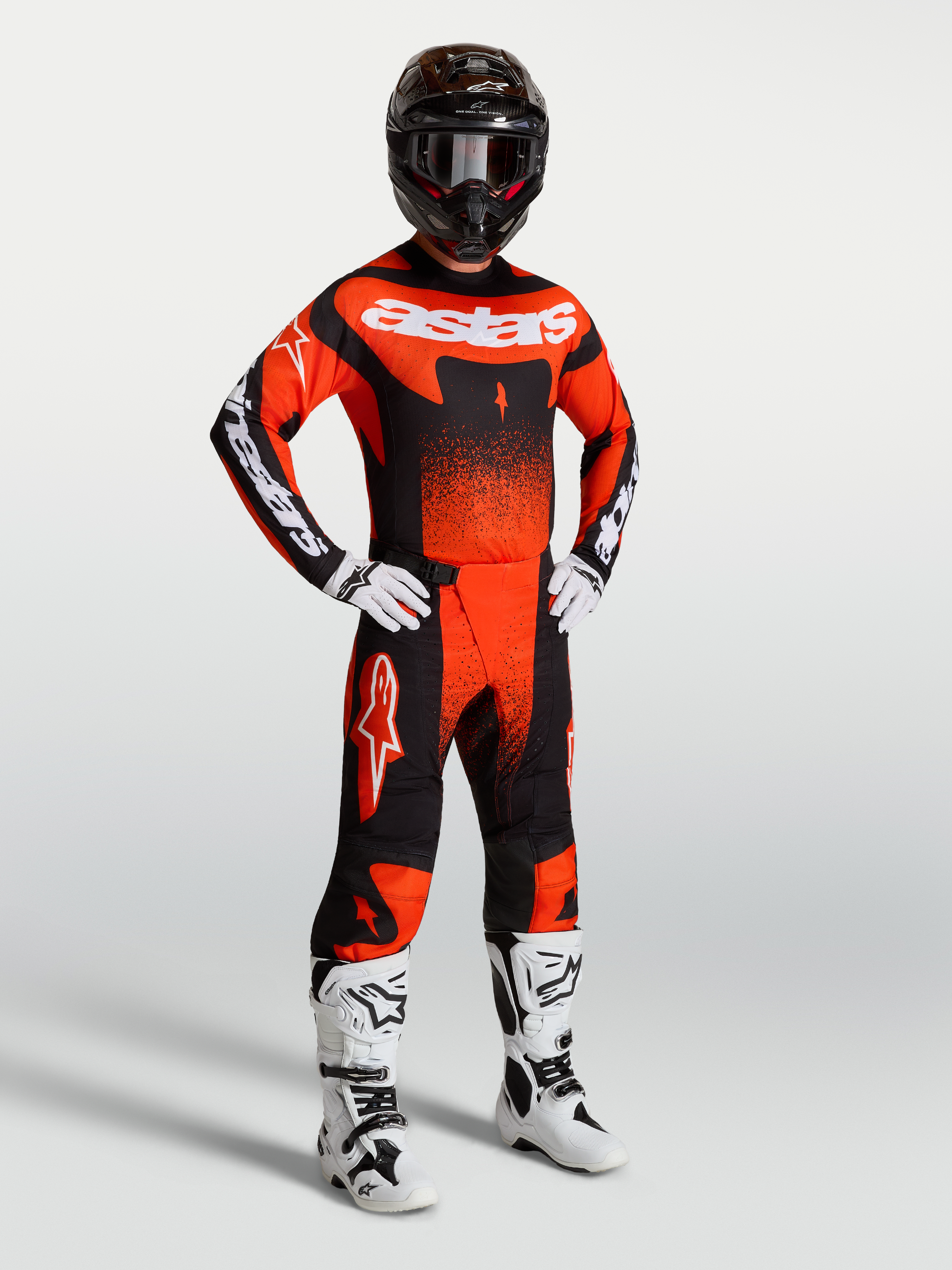 Alpinestars Techstar Swan broek, heren-motorcrossbroek in rood, zwart en wit, gedragen met bijpassende jersey en laarzen.