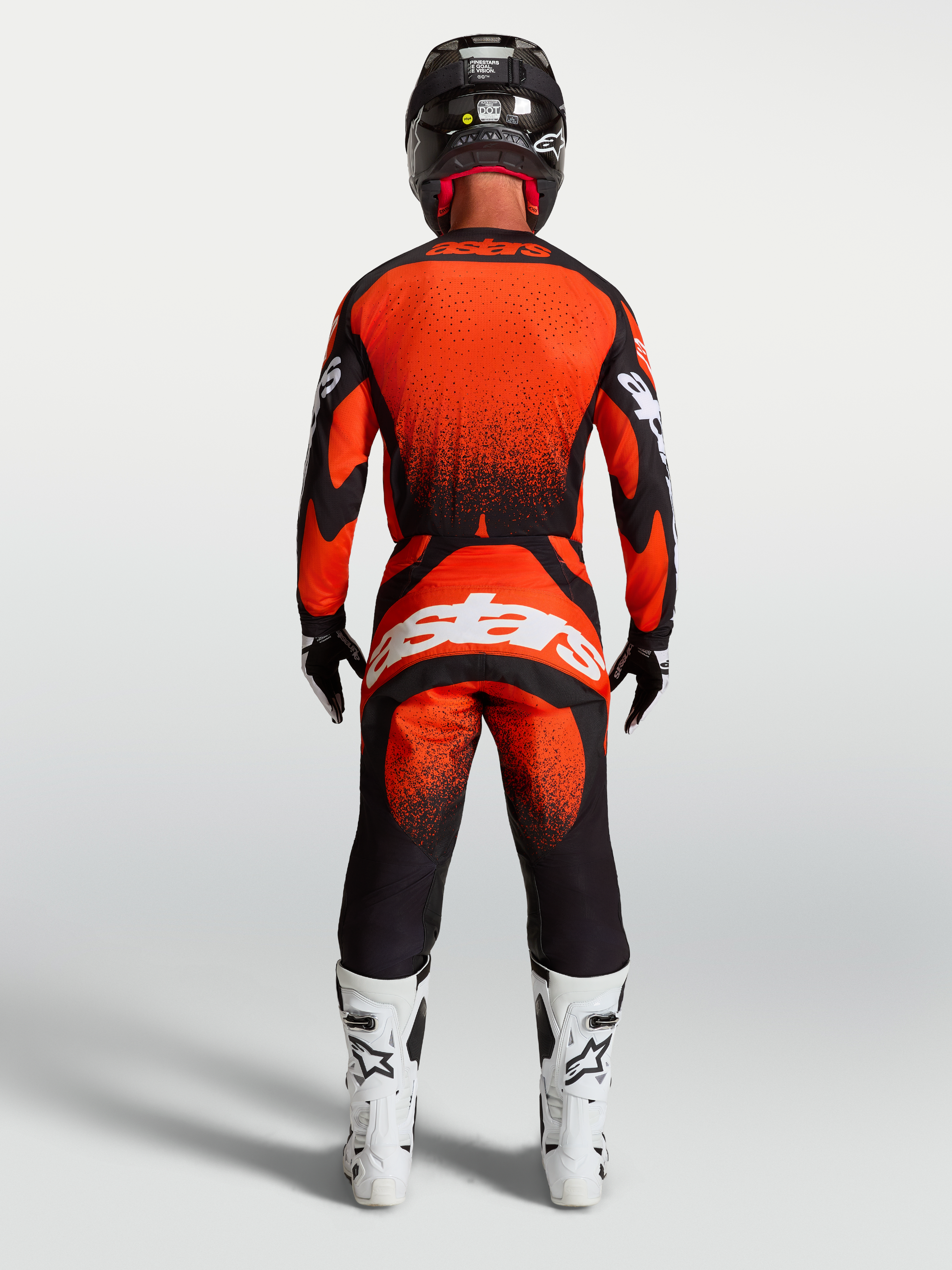 Alpinestars Techstar Swan broek, rode en zwarte motorcrossbroek voor heren, achteraanzicht op model met witte motorlaarzen.
