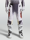 Alpinestars Techstar Swan, pantalon de motocross gris et lilas avec accents rouges, boucle magnétique et motif graphique.