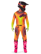 Motocross-Fahrer in der Alpinestars 2025 Supertech Lipan Ausrüstung mit lebhaftem Gelb-Pink-Farbverlauf, passendem langärmeligem Trikot, leuchtend pinken Stiefeln, lindgrünen Handschuhen und schwarzem Helm mit orangefarbener Brille.
