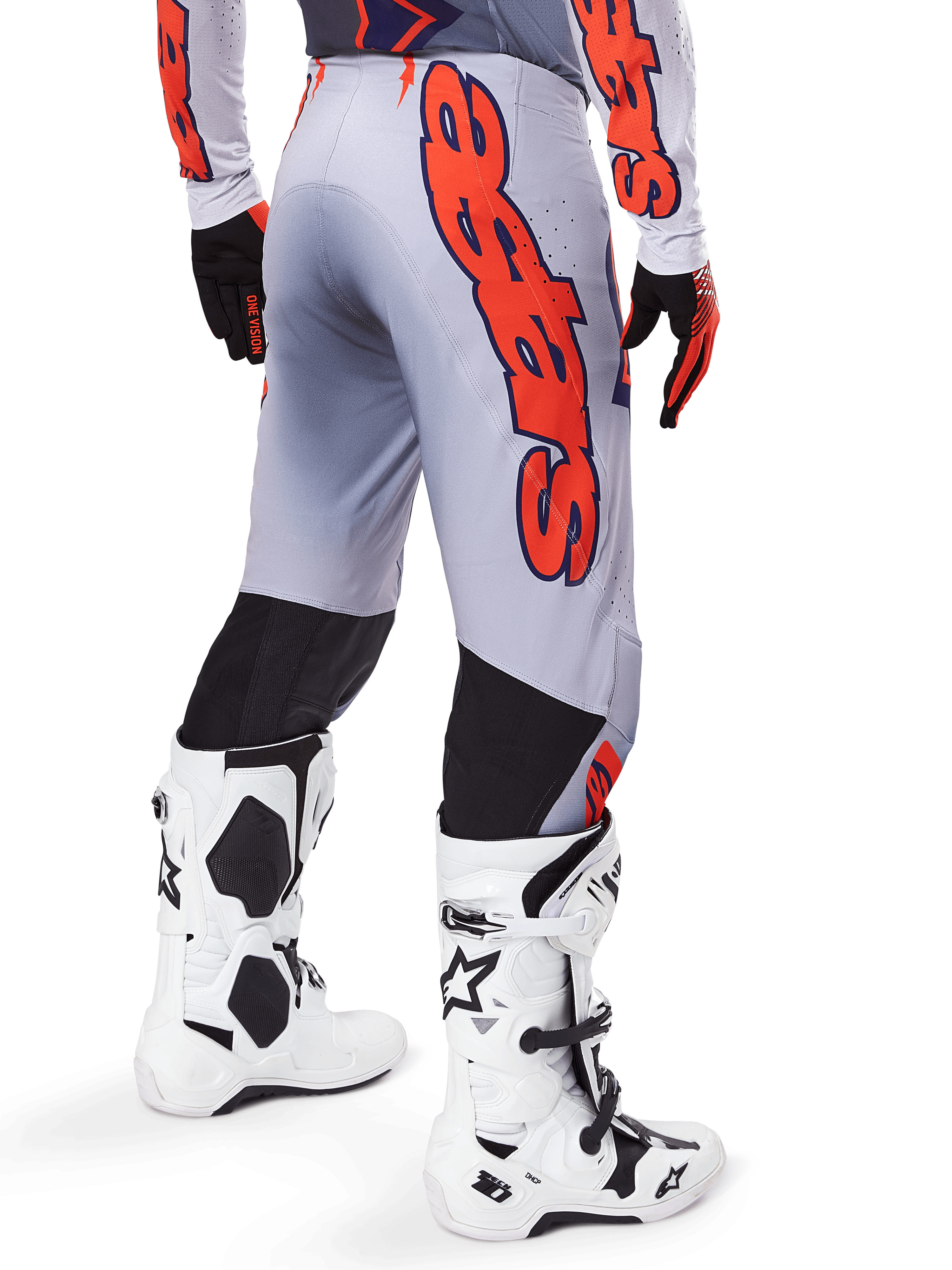 Pantalon Alpinestars Supertech Lipan 2025, pantalon de motocross, gris et orange fluo, porté avec le maillot assorti et des bottes blanches, vue arrière avec grand graphisme Alpinestars orange, empiècements extensibles noirs, équipement de course professionnel