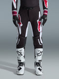 Alpinestars 2026 Supertech AFD Vista Pants, Motocross Pants, Black Red and White, featuring large graphic logos on the thighs and knees, worn with white racing boots and black gloves, athletic race-ready design for elite off-road competition